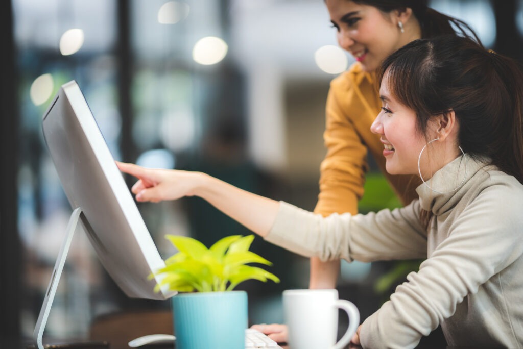 group of students smiling in an office while discussing something on screen