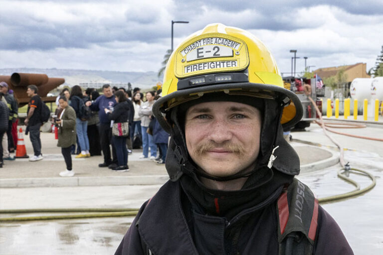 A smiling student firefighter in the foreground with others standing behind him