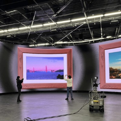 two students in front of a screen with video equipment