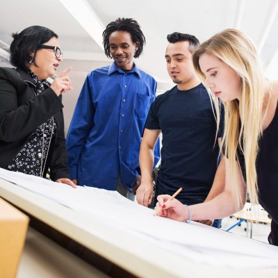 Four people gathered around a drafting table